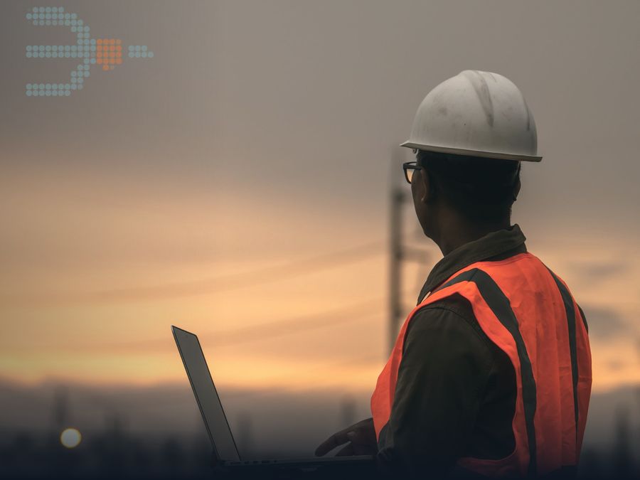 Field engineer in a hard hat at sunset